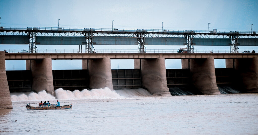imagem de uma usina hidrelétrica no fundo com o nivel de agua baixo, por conta da crise hídrica